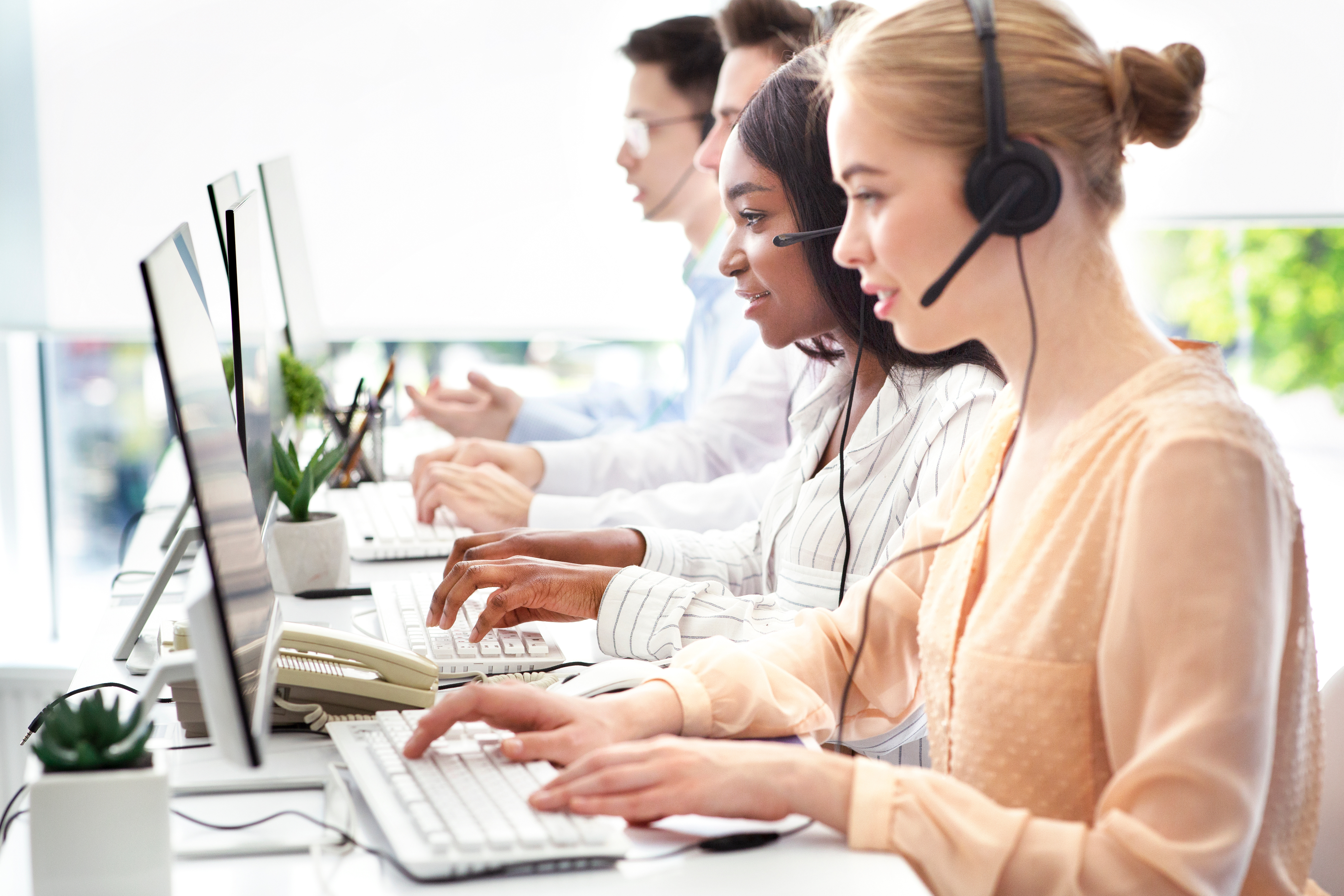 Contact center agents answering customer calls at their workstations.
